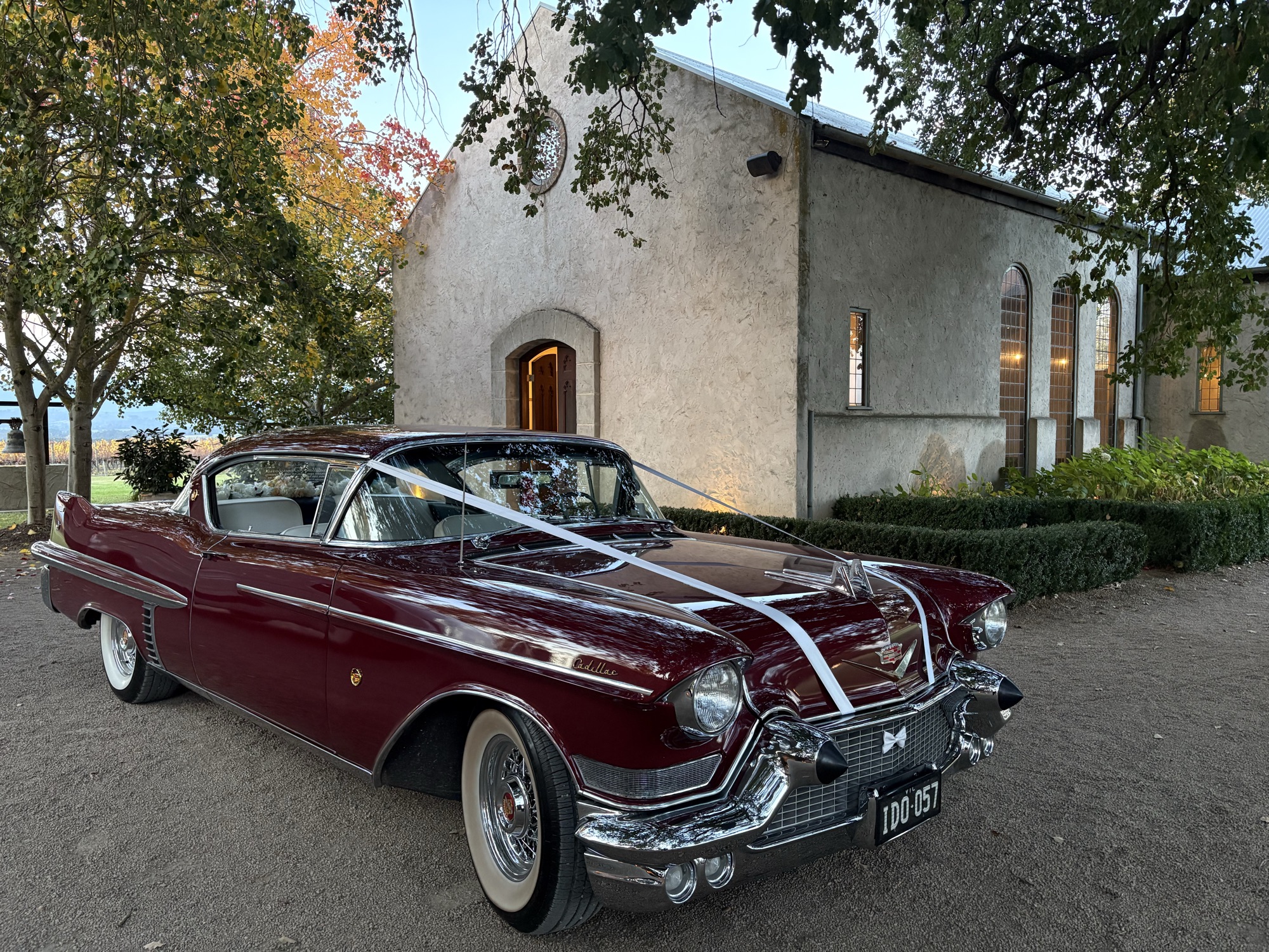 ELLIE Mae the maroon classic Cadillac coupe with wedding ribbon parked outside a country chapel