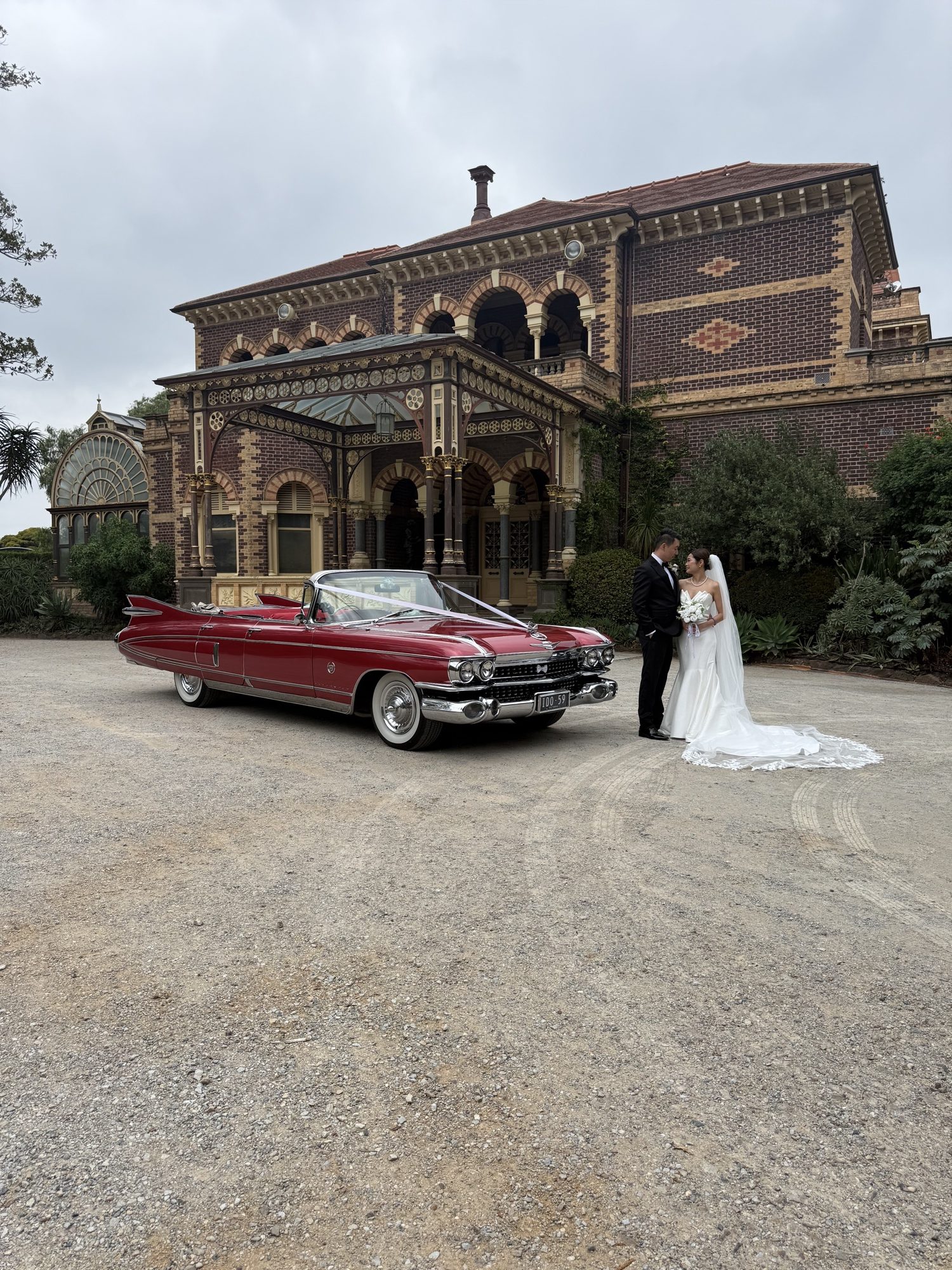 Rosie the rose pink Cadillac convertible parked outside a grand heritage stone building