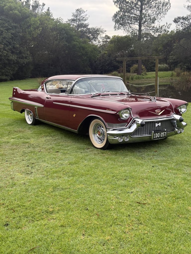 ELLIE Mae, Caddyman's maroon classic Cadillac coupe, parked on a lawn, front three-quarter view