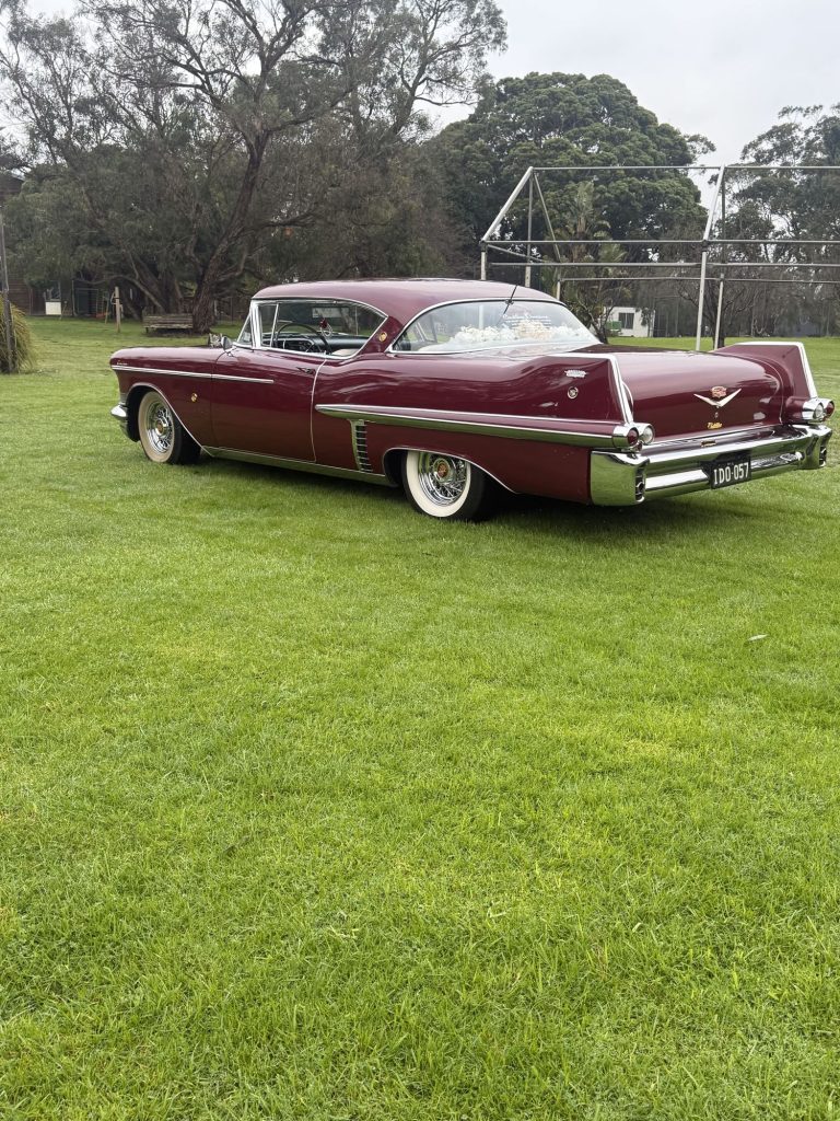 ELLIE Mae, Caddyman's maroon classic Cadillac coupe, parked on a lawn, side view