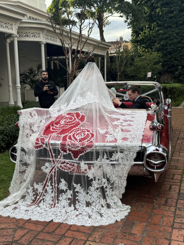 Lace veil draped across the tail fins of Rosie, Caddyman's 1959 Rose Pink Pearl Cadillac convertible
